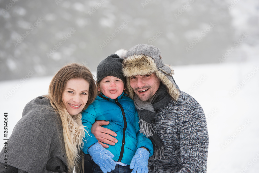 Father and mother with their son, playing in the snow.