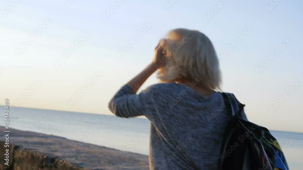 Beautiful girl walks with her colorful bag smiling near the beach at sunrise Beautiful girl walks with her colorful bag smiling near the beach at sunrise