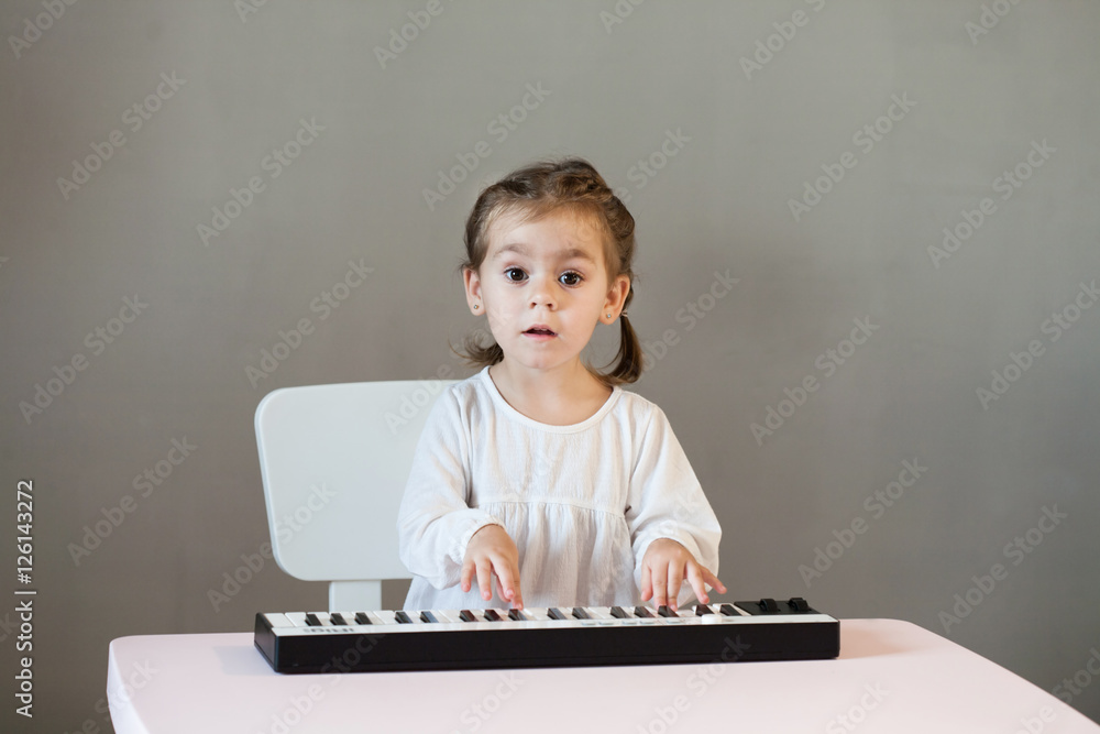 Cute little girl in white shirt playing electronic piano. Process of education, cognition Cute little girl in white shirt playing electronic piano. Process of education, cognition