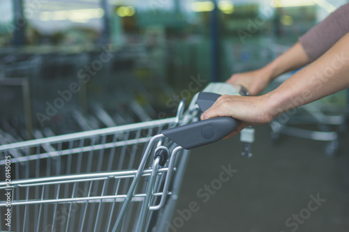 Hands of woman pushing shopping trolley