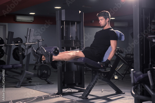 young man sitting leg extension gym