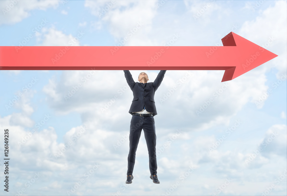 Obraz premium Businessman hanging freely on giant red arrow