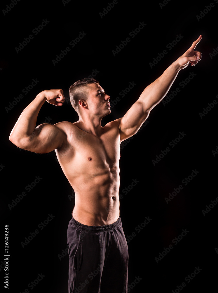 young bodybuilder man pointing isolated on black background