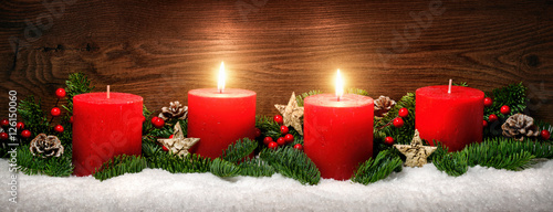 Advent Dekoration mit zwei Kerzenflammen, Schnee, Tannenzweigen und Holz Hintergrund photo