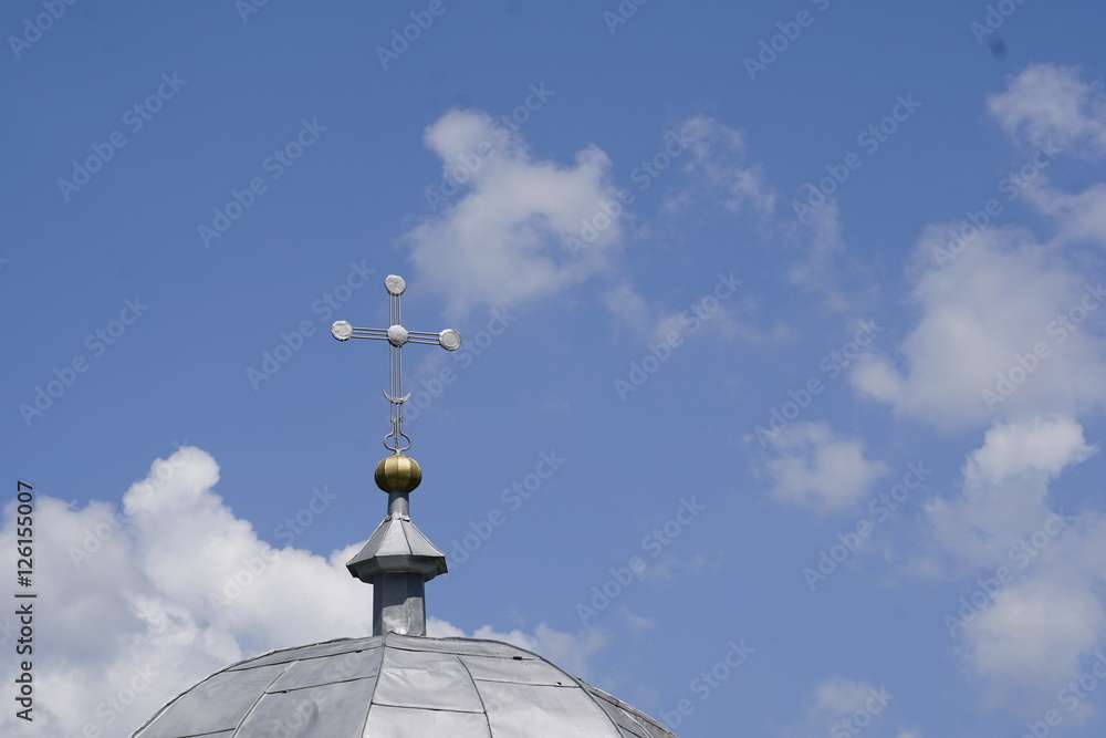 cross on top of a church in front of bright blue sky