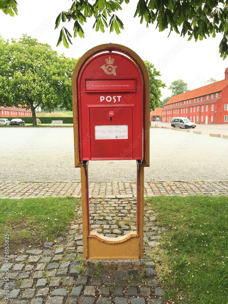 Roter Briefkasten mit Aufschrift Post auf gelber Stütze Roter Briefkasten mit Aufschrift Post auf gelber Stütze