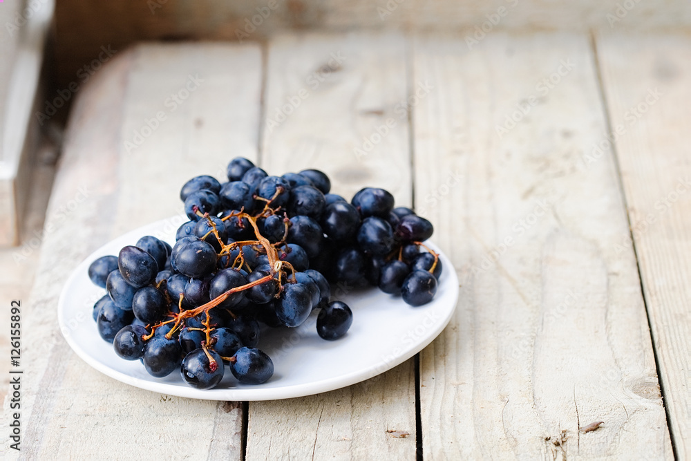 Bunch of ripe blue grapes on a light wooden background Bunch of ripe blue grapes on a light wooden background