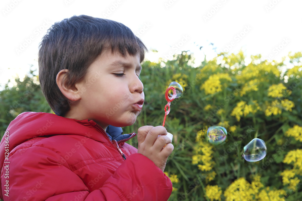 kid doing soap bubbles in a background with flowers kid doing soap bubbles in a background with flowers