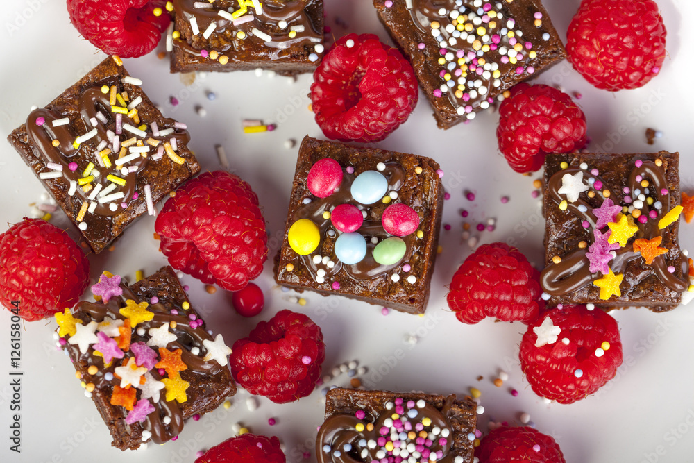Candy topped chocolate brownies and raspberries viewed from abov