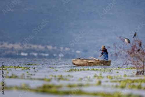 Traditional Mexican fishermen throwing fishing net at lake chapa