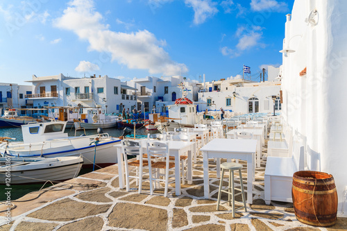 White taverna tables and fishing boats in Naoussa port, Paros island, Greece
