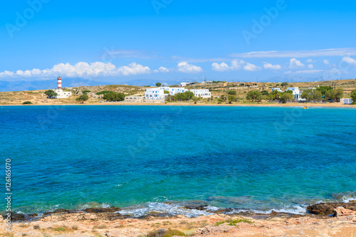 Blue sea bay with lighthouse and holiday apartments in distance in Naoussa town, Paros island, Greece © pkazmierczak