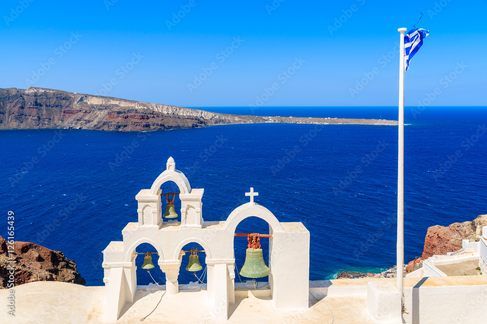 Fototapeta premium Church tower and Greek flag against blue sea on Santorini island, Greece