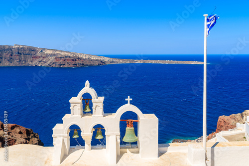 Church tower and Greek flag against blue sea on Santorini island, Greece