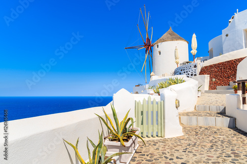 Typical white windmill on street of Oia village, Santorini island, Greece