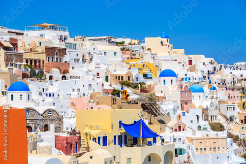 Colorful houses and churches with blue domes in Oia village on Santorini island, Greece