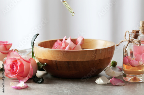 Pipette with aroma oil and flowers in wooden bowl