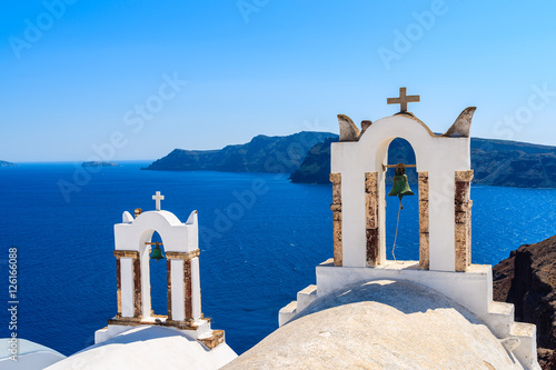 White church towers in Oia village against blue sea background on Santorini island, Greece