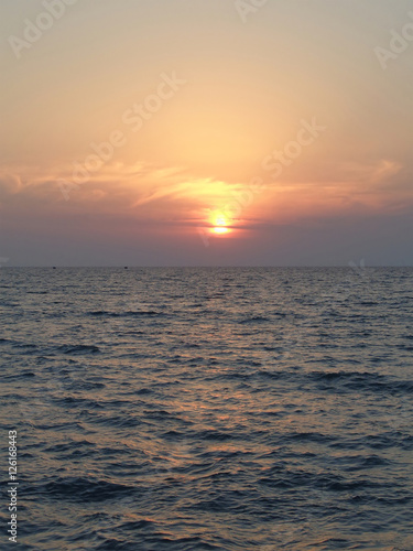 Fototapeta Naklejka Na Ścianę i Meble -  Морской закат, вечернее солнце в дымке облаков