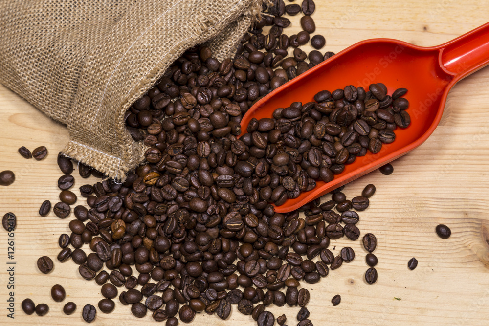 Coffee beans in an old bag and a spoon on wooden table Coffee beans in an old bag and a spoon on wooden table
