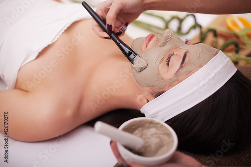 Spa therapy for young woman having facial mask at beauty salon - indoors