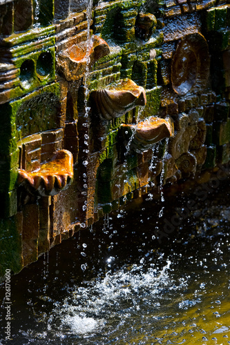 Fototapeta Naklejka Na Ścianę i Meble -  Overgrown old mossy fountain with falling drops of water 