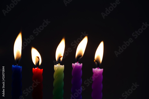 Colorful candles on black background. Blue red green violet pink candle with real flame. Soft focus