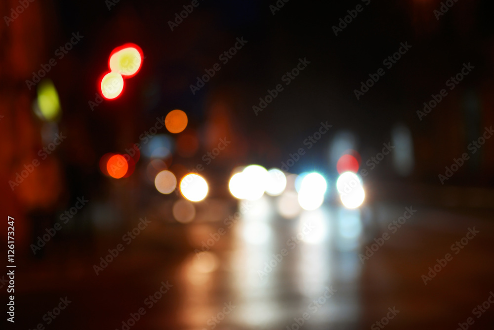 NIht in the city blurred shot. Cars in the street with reflections of carlights in asphalt road surface shot with space for text