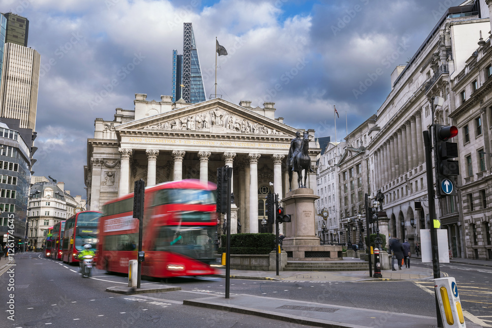 London, England - The Royal Exchange building with moving red double decker buses
