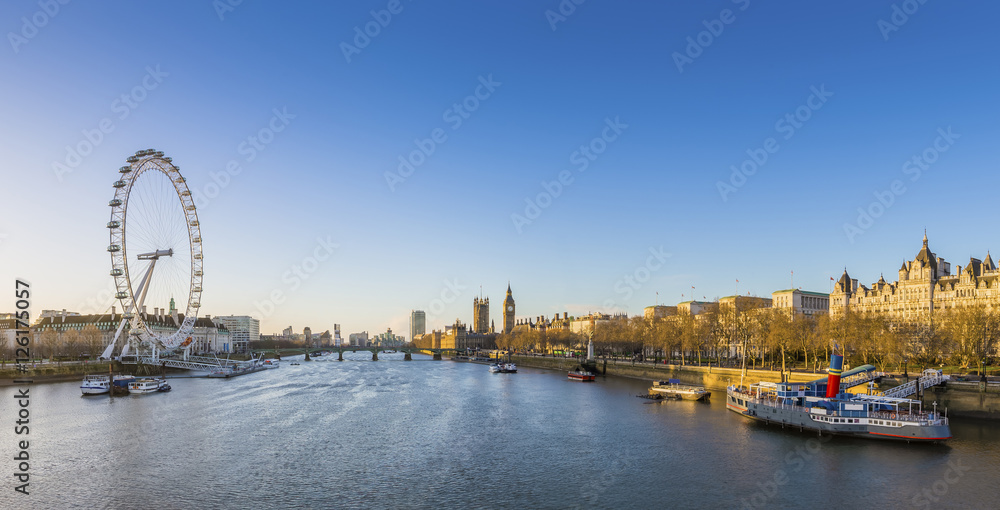 London skyline view at sunrise with famous landmarks, Big Ben, Houses of Parliament and ships on River Thames with clear blue sky - England, UK