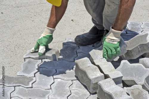 Construction worker laying concrete tiles