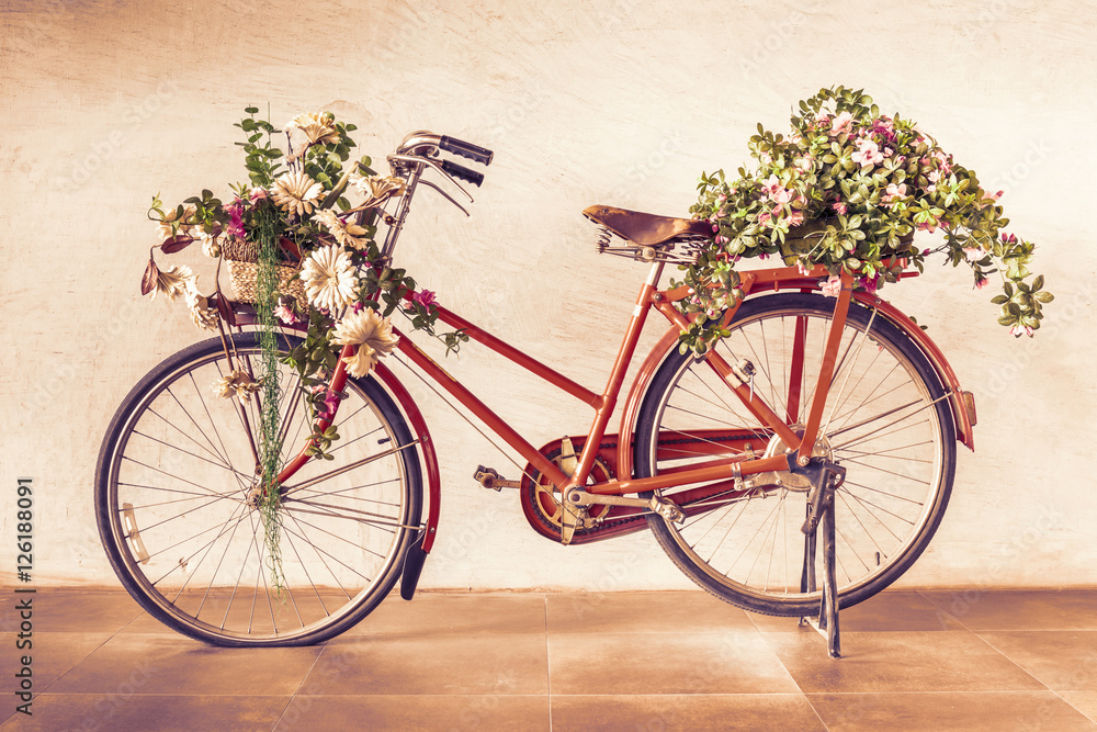 Vintage style of red bicycle with flower baskets parking against