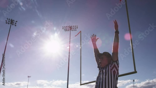 A football referee raises hands over his head for a field goal