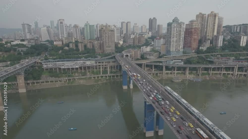 Aerial view of a commuter metro train riding over a bridge past a traffic jam in Chongqing, China Aerial view of a commuter metro train riding over a bridge past a traffic jam in Chongqing, China