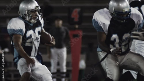 A football player runs with the ball while players trying to tackle him miss