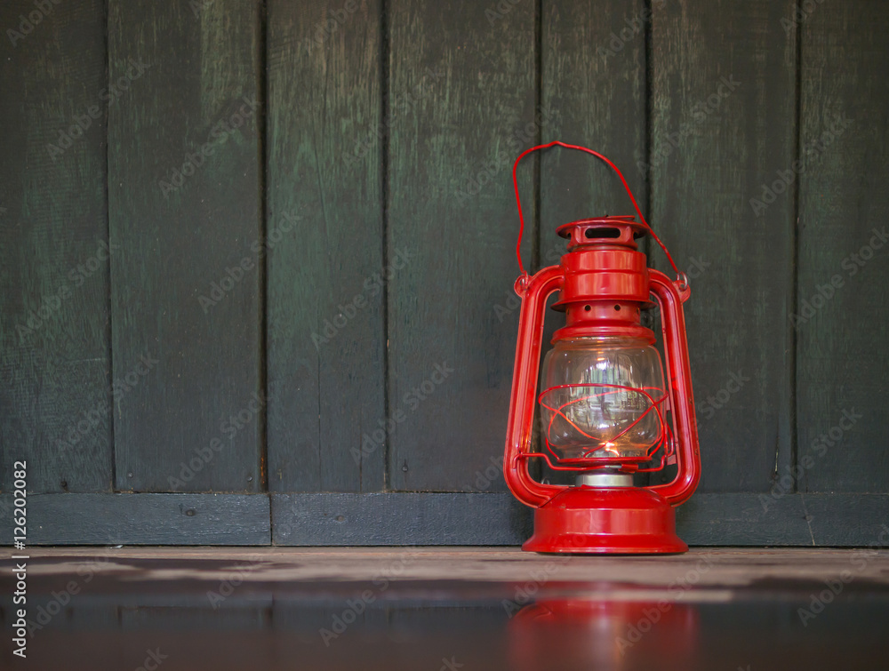 a red old lantern on the dark wet wooden floor with reflection o
