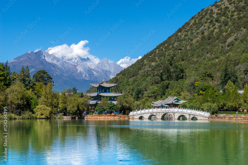 Black Dragon Pool to the Five Phoenix Tower and the Five Holes Bridge. In the background is Yulong Xue Shan (Jade Dragon Snow Mountain). The Old Town of Lijiang, Yunnan, China.