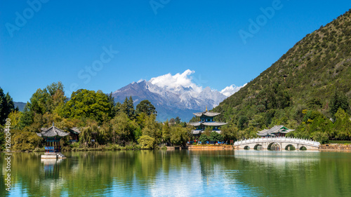 Black Dragon Pool to the Five Phoenix Tower and the Five Holes Bridge. In the background is Yulong Xue Shan (Jade Dragon Snow Mountain). The Old Town of Lijiang, Yunnan, China.