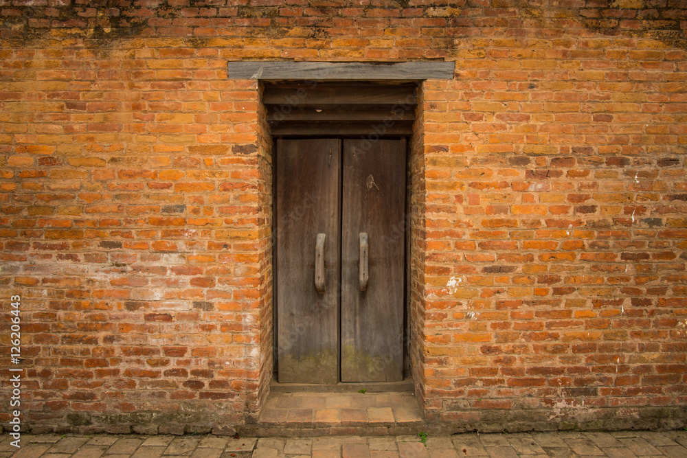 The orange brick wall and the old door in the middle of the wall in Kathmandu, Nepal.