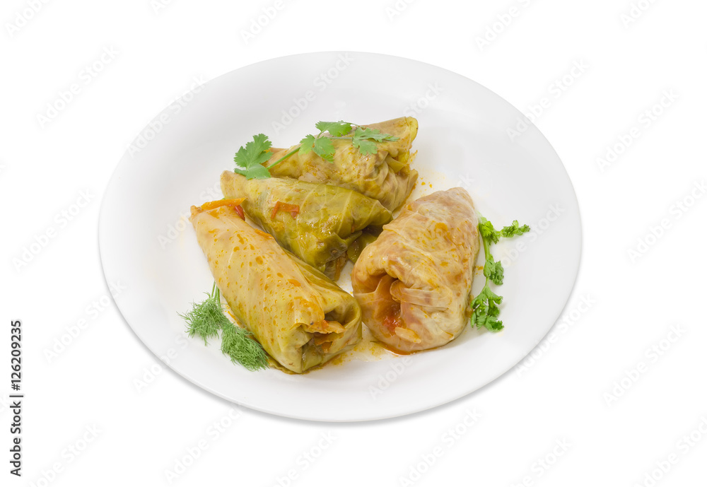 Cooked cabbage rolls and twigs of greenery on white dish