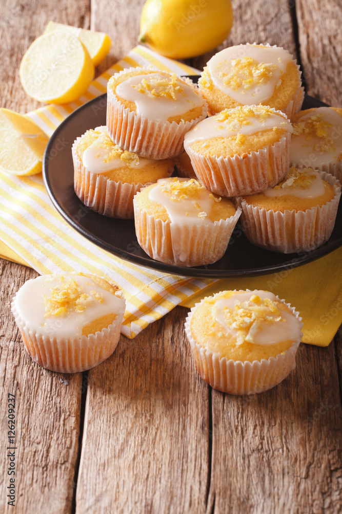 Breakfast muffins with lemon zest and icing closeup on a plate. vertical Breakfast muffins with lemon zest and icing closeup on a plate. vertical