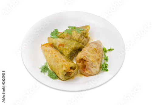 Cooked cabbage rolls and twigs of greenery on white dish