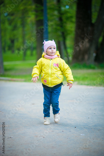 Fototapeta Naklejka Na Ścianę i Meble -  Funny baby girl in a yellow coat and pink hat
