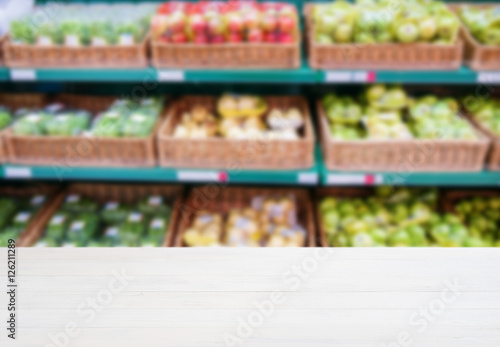Wooden empty table in front of blurred supermarket vegetables shelf © fascinadora