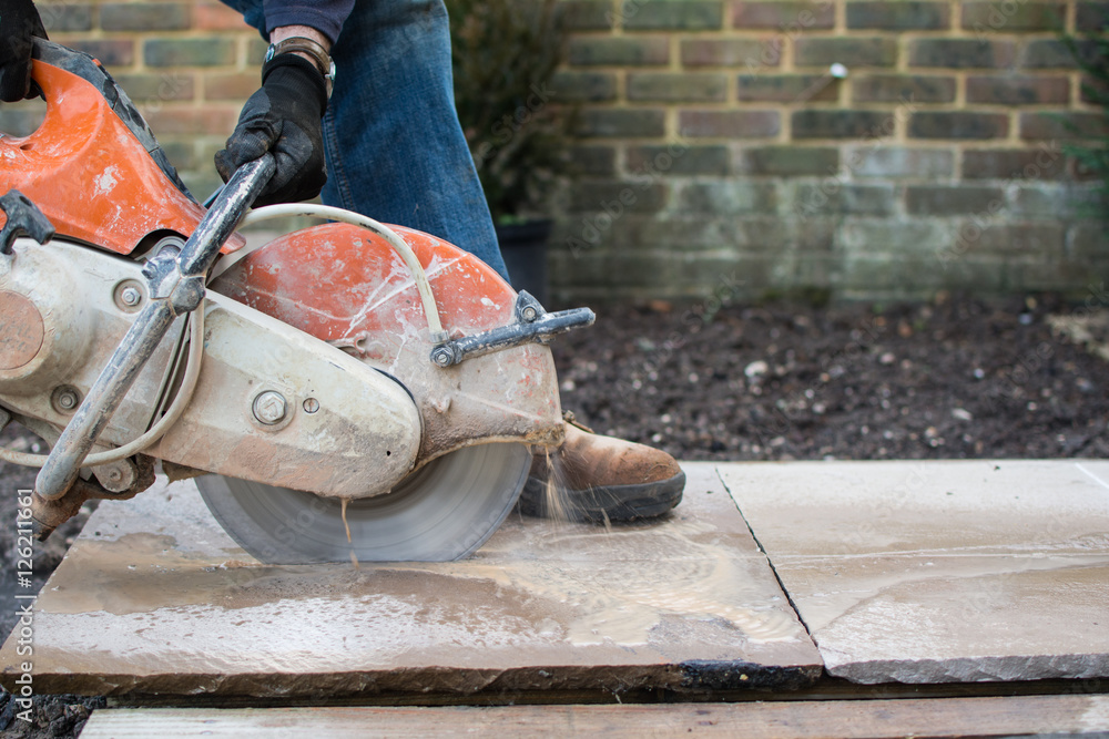 Man using the discutter in the garden to cut the indian sandstone slabs; picture in motion Man using the discutter in the garden to cut the indian sandstone slabs; picture in motion