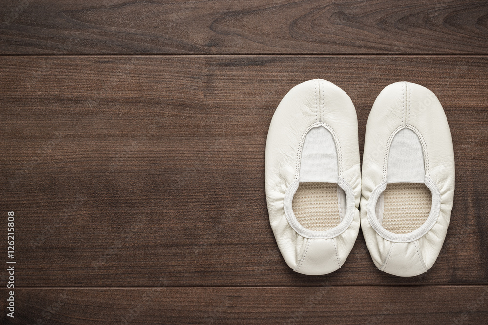 child's white dancing shoes on the wooden floor child's white dancing shoes on the wooden floor