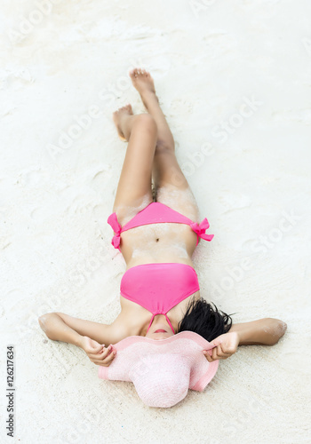 Beautiful young girl lying on the sand, sunbathing