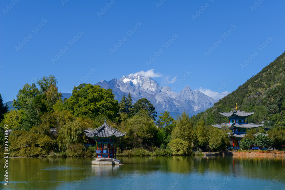 Black Dragon Pool to the Five Phoenix Tower and the Five Holes Bridge. In the background is Jade Dragon Snow Mountain. The Old Town of Lijiang is located in Lijiang City, Yunnan, China.