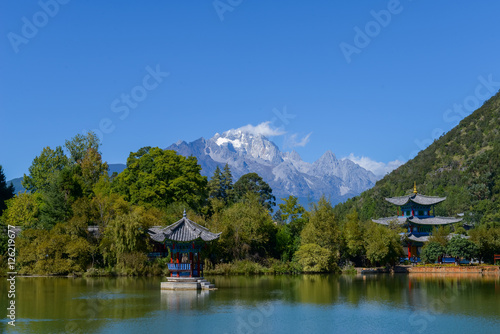 Black Dragon Pool to the Five Phoenix Tower and the Five Holes Bridge. In the background is Jade Dragon Snow Mountain. The Old Town of Lijiang is located in Lijiang City, Yunnan, China.