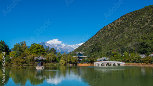 Black Dragon Pool to the Five Phoenix Tower and the Five Holes Bridge. In the background is Jade Dragon Snow Mountain. The Old Town of Lijiang is located in Lijiang City, Yunnan, China. © joesayhello